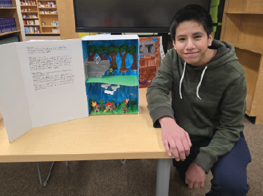 student smiling next to literacy project